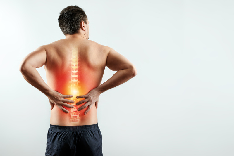 Rear view, the man holds his hands behind his back, pain in the back, pain in the spine, highlighted in red.